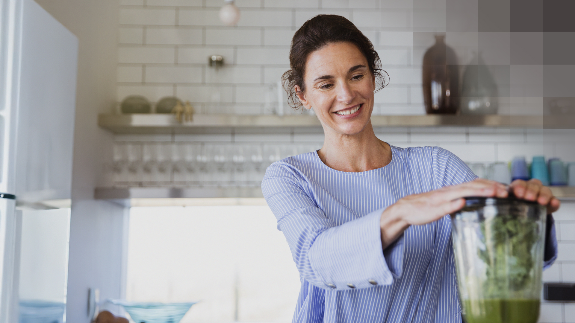 Une femme prépare un smoothie vert dans sa cuisine et pense à son assurance dentaire complémentaire.