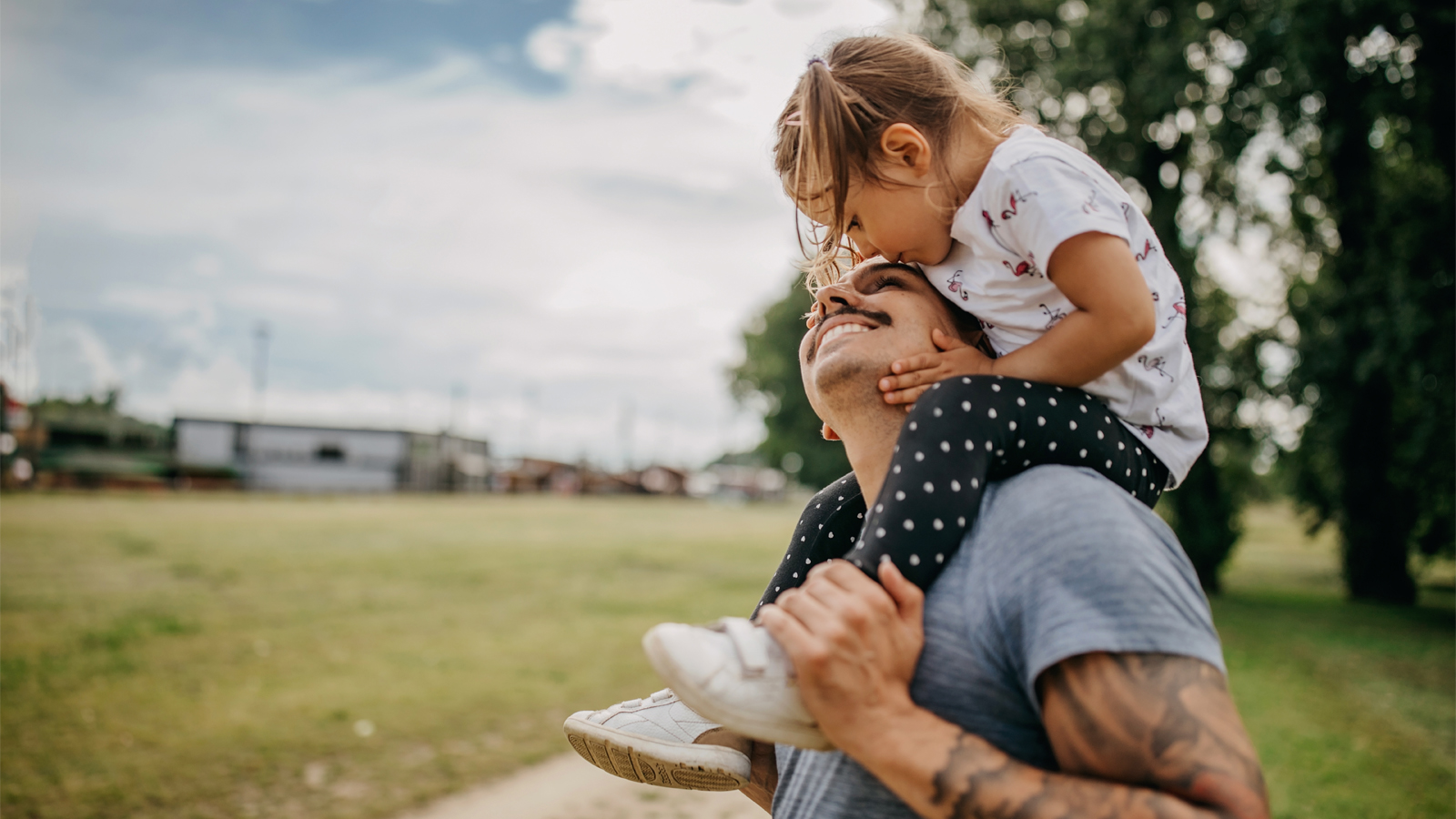 Un père porte sa fille sur ses épaules et se réjouit d’avoir une bonne assurance maladie pour enfants.