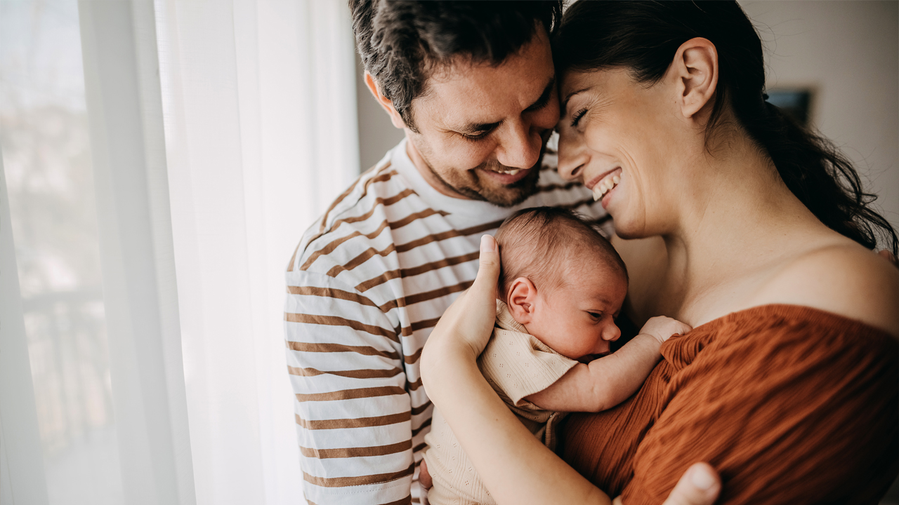 A happy couple with their baby after registering it before birth and taking out supplementary health insurance.