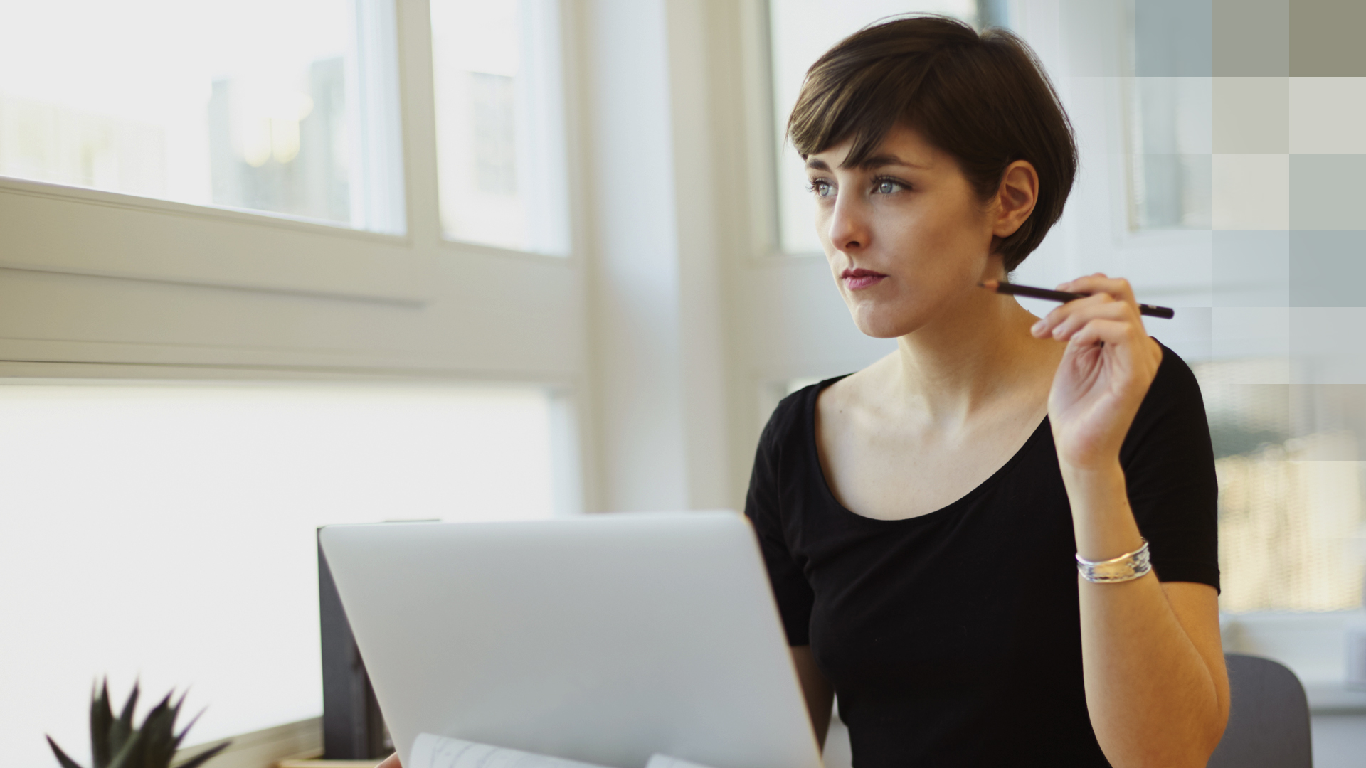Une femme est assise devant son ordinateur portable et réfléchit à son assurance protection juridique.