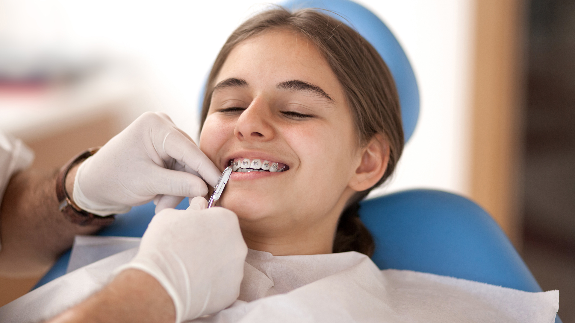 Jeune patiente portant un appareil dentaire lors d’un contrôle chez le dentiste en cabinet dentaire – Que paie l’assurance maladie pour un appareil dentaire?