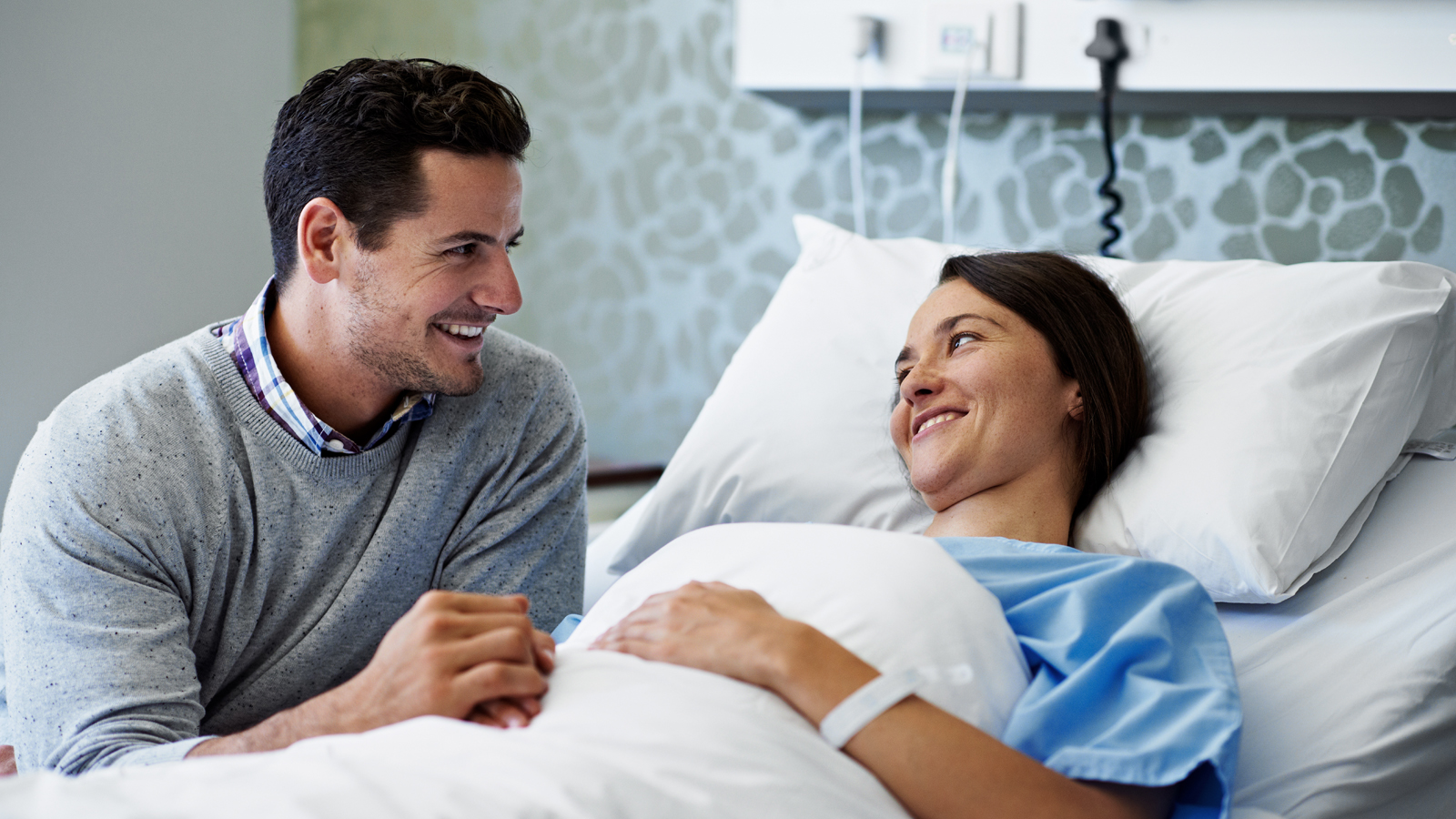 Un homme rend visite à sa femme dans une chambre d’hôpital privée grâce à une assurance hospitalisation privée