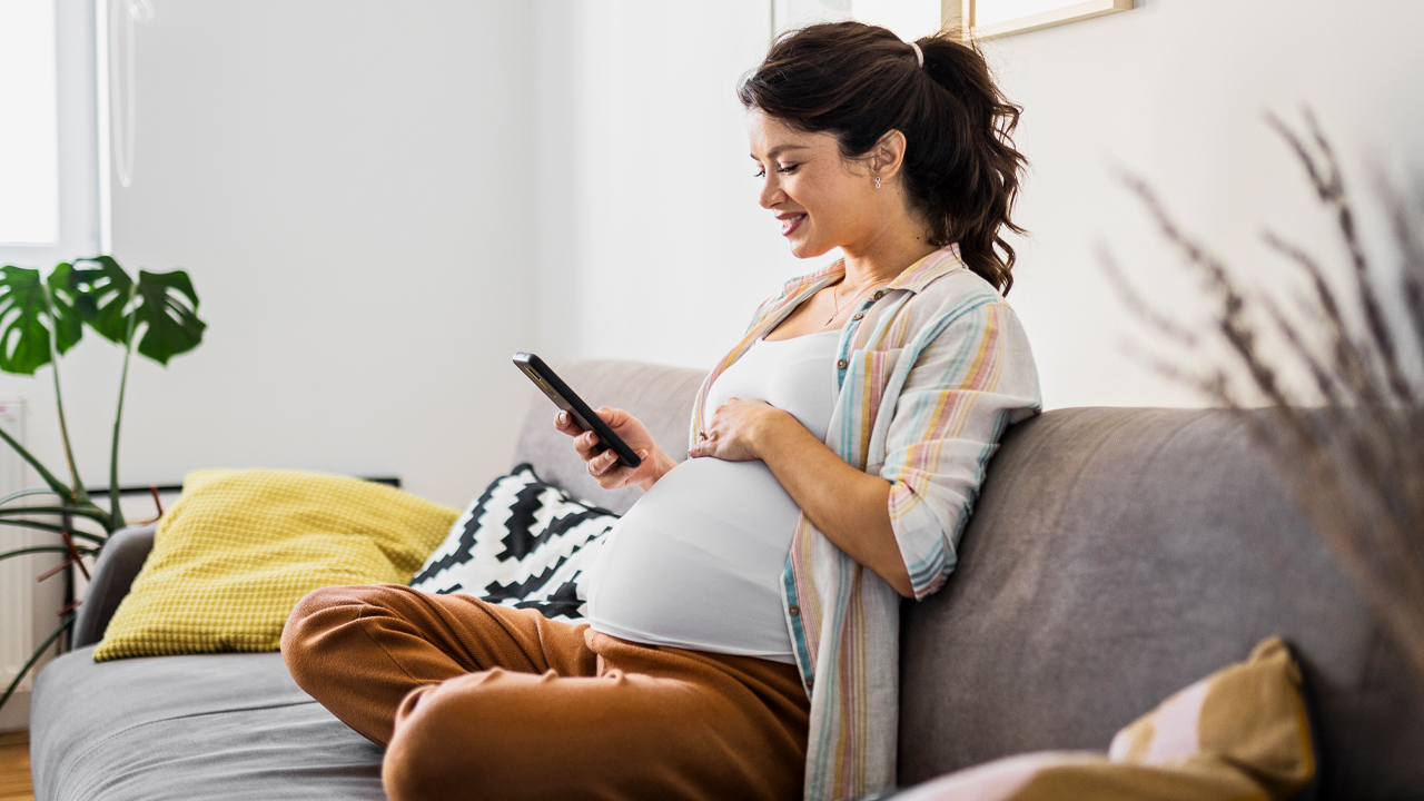 A pregnant woman researching prenatal registration on her mobile phone