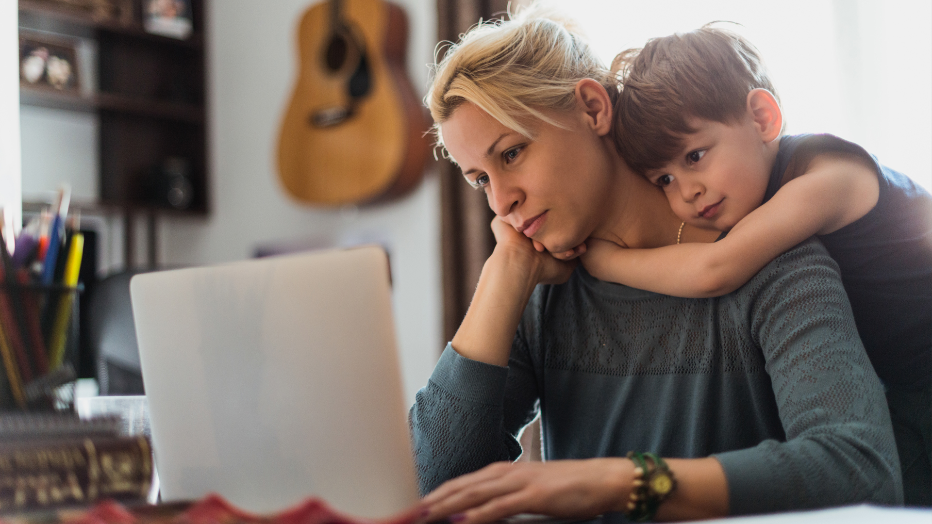 Mental Load: Eine Mutter am Laptop mit ihrem Sohn