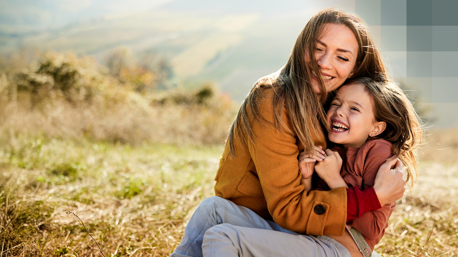 Une mère serre son enfant dans ses bras dans un pré et est heureuse d’avoir une assurance vie risque pur.