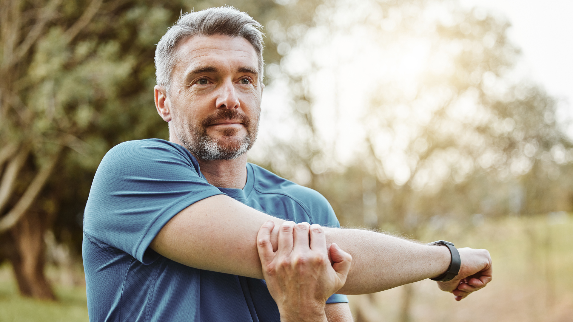 Homme d'environ 50 ans s'étirant en plein air : rester actif pour mieux gérer l'andropause (ménopause masculine).