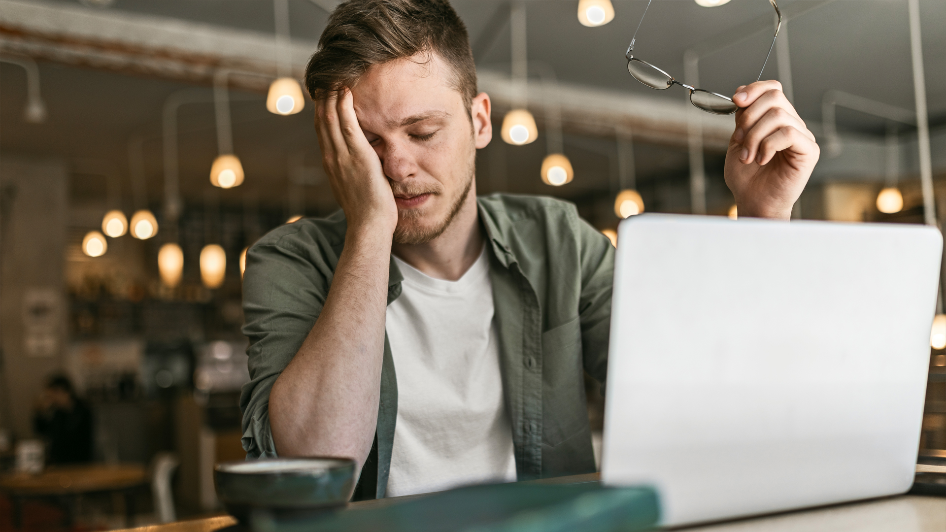 Ein müder Mann sitzt am Laptop, weil er an Schlafapnoe leidet.